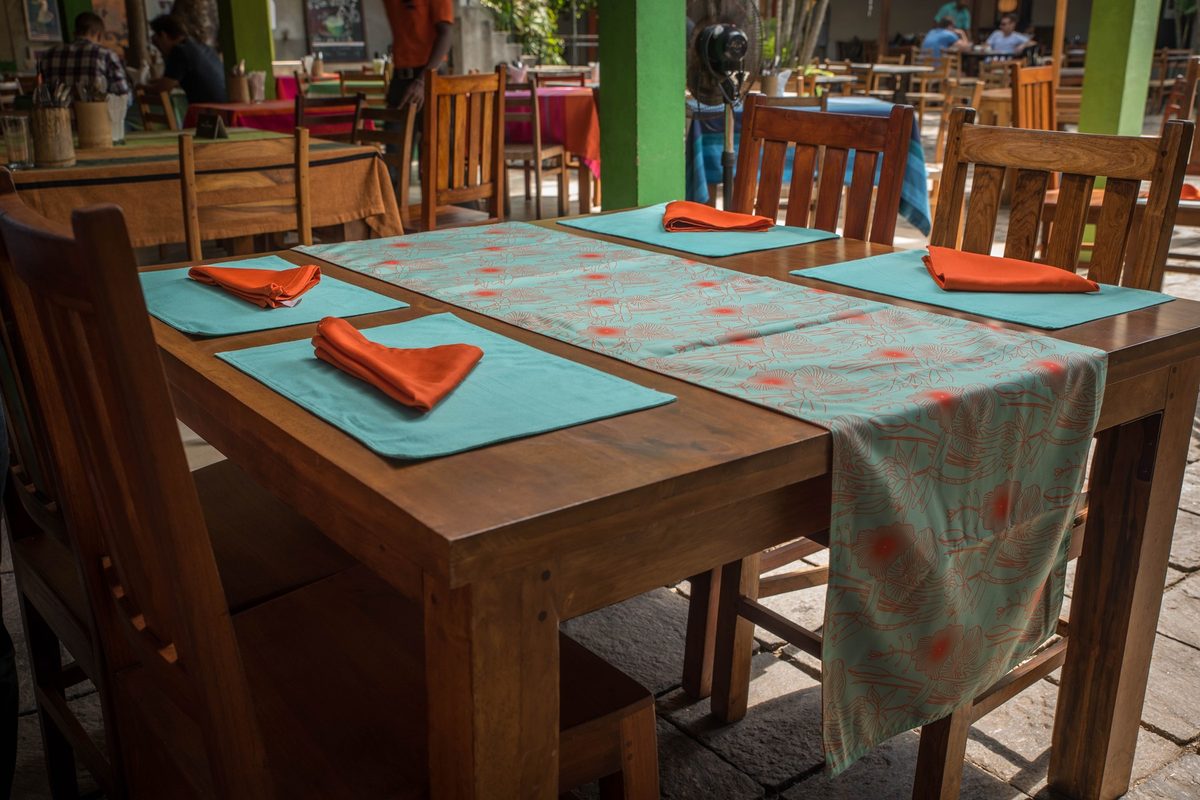 Floral table runner with teal placemats and orange napkins